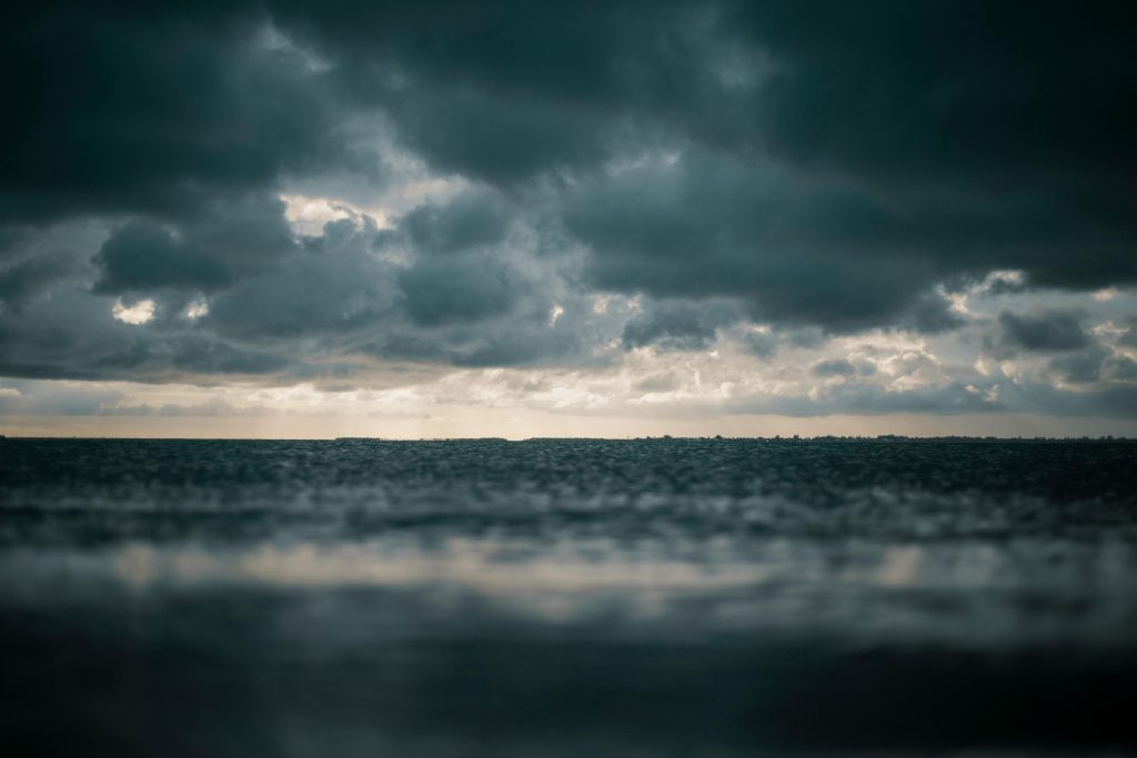Dark grey storm clouds over deep blue waters.